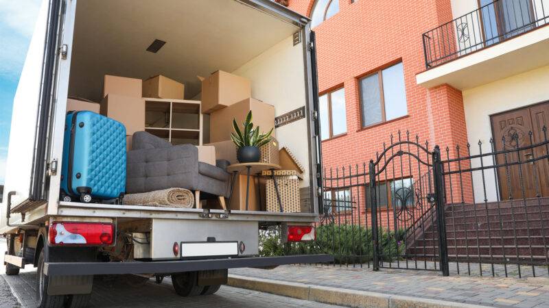 Lieferwagen voller Umzugskartons und Möbel in der Nähe eines Hauses