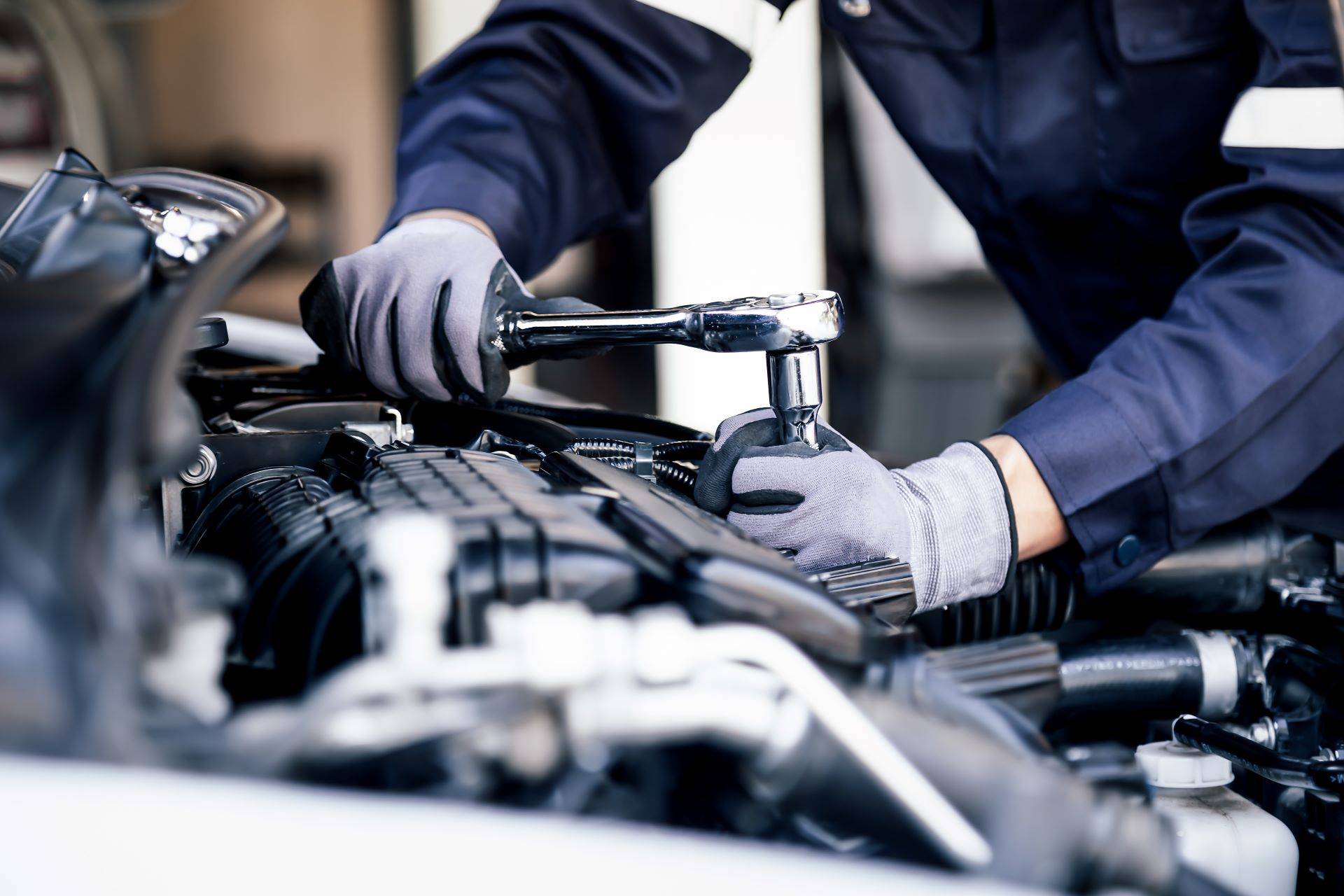 Mechaniker arbeitet mit Ratsche an Fahrzeugmotor