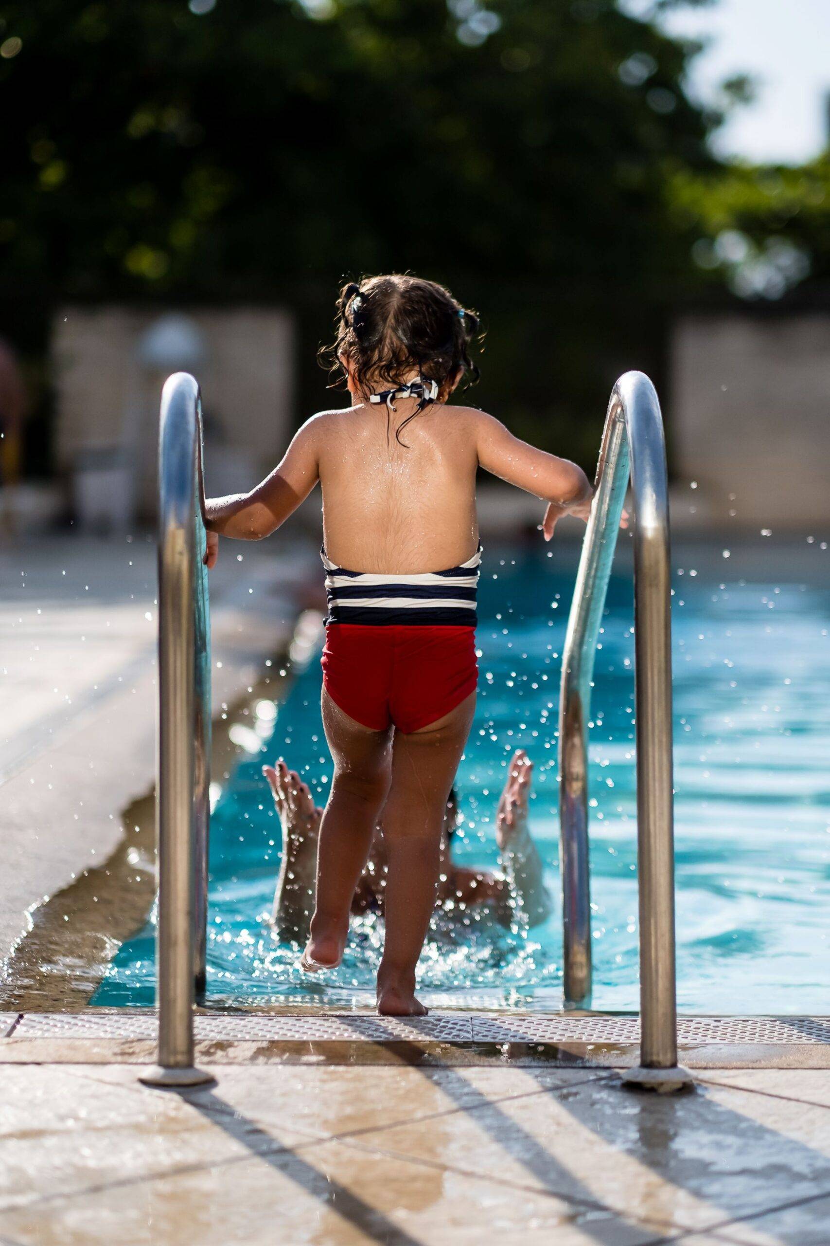 Kind nutzt Pool Treppe aus Edelstahl zum sicheren Einstieg ins Wasser, familienfreundliche Ausstattung fuer Pools
